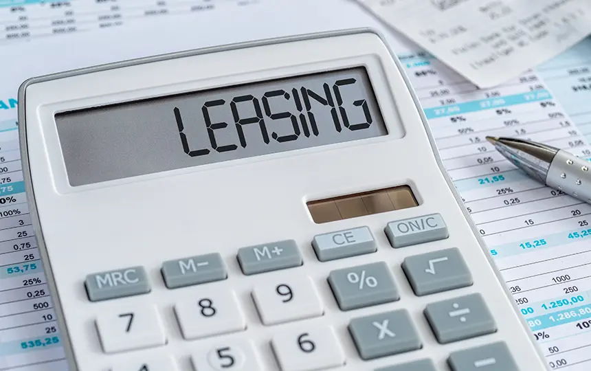 ディスプレイに「LEASING」と表示された電卓と会計書類・ペン(新リース会計基準の導入に伴う財務影響や試算をイメージしたカット)